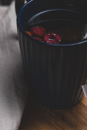 A cup of tea with raspberries in tea