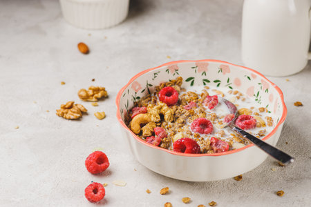 A plate with granola and raspberries, filled with milkの写真素材