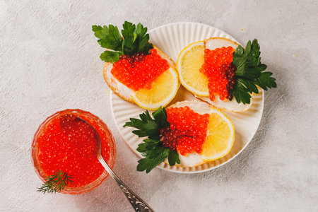 Sandwiches with red caviar, a slice of lemon, and a sprig of parsleyの写真素材