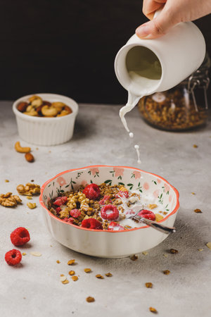 A plate with granola and raspberries, filled with milkの写真素材