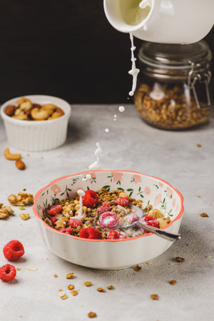 A plate with granola and raspberries, filled with milkの写真素材