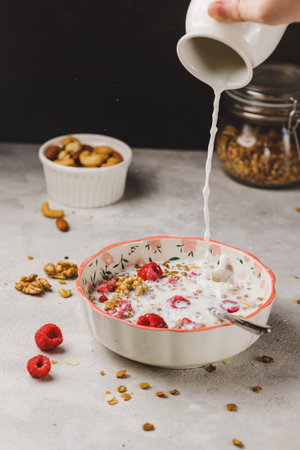 A plate with granola and raspberries, filled with milkの写真素材