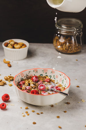A plate with granola and raspberries, filled with milkの写真素材