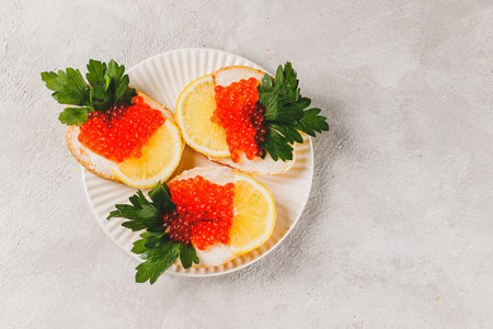 Sandwiches with red caviar, a slice of lemon, and a sprig of parsleyの写真素材
