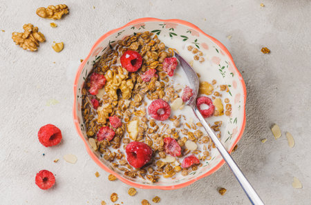 A plate with granola and raspberries, filled with milkの写真素材