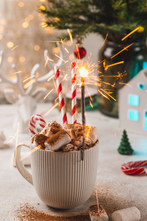 A sparkler is burning in a mug with marshmallows and cocoaの写真素材