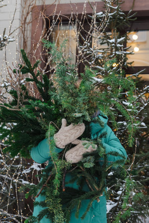 The girl holds an armful of coniferous branches with her hands
