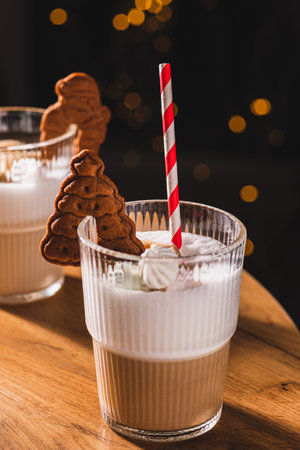 Glasses with coffee and high milk foam. There's a straw in the glass and a cookie on the edgeの写真素材