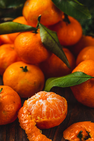 Peeled tangerine on a wooden table among other tangerinesの写真素材