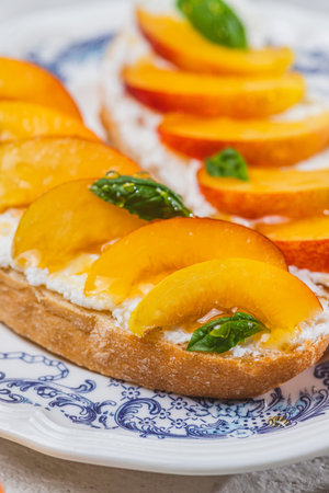 Bruschetta with ricotta cheese, sliced nectarines, basil and honey on a plateの写真素材
