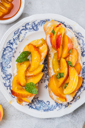 Bruschetta with ricotta cheese, sliced nectarines, basil and honey on a plateの写真素材