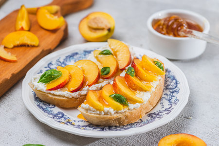 Bruschetta with ricotta cheese, sliced nectarines, basil and honey on a plateの写真素材
