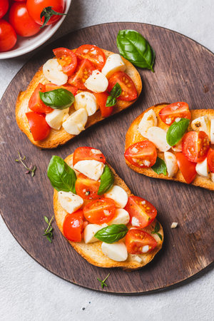 Bruschetta caprese with cherry tomatoes and mozzarella garnished with basilの写真素材