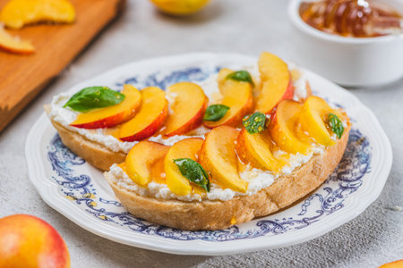 Bruschetta with ricotta cheese, sliced nectarines, basil and honey on a plateの写真素材