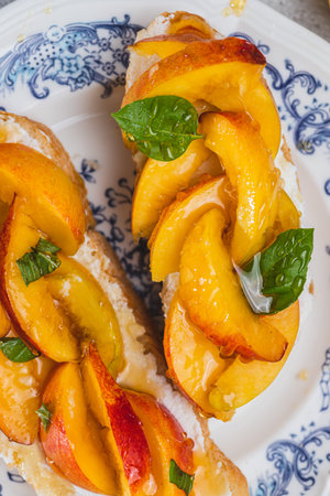 Bruschetta with ricotta cheese, sliced nectarines, basil and honey on a plateの写真素材