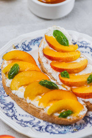 Bruschetta with ricotta cheese, sliced nectarines, basil and honey on a plateの写真素材