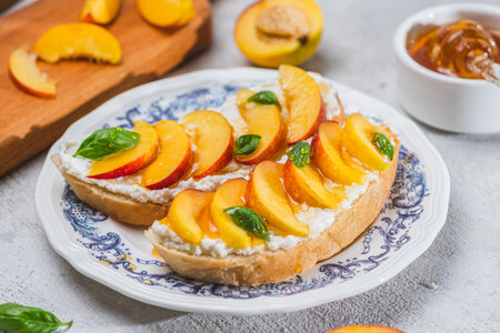 Bruschetta with ricotta cheese, sliced nectarines, basil and honey on a plateの写真素材