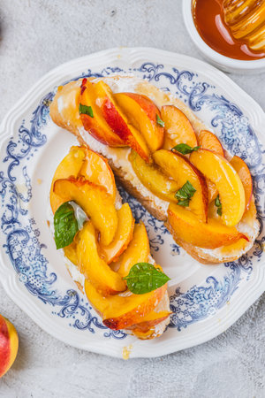 Bruschetta with ricotta cheese, sliced nectarines, basil and honey on a plateの写真素材