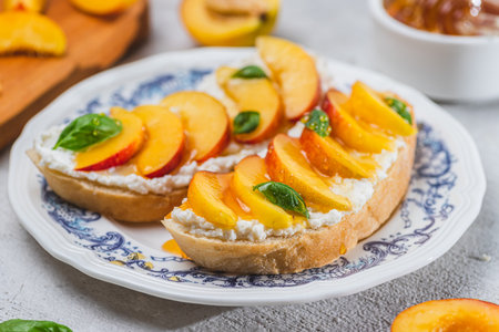 Bruschetta with ricotta cheese, sliced nectarines, basil and honey on a plateの写真素材