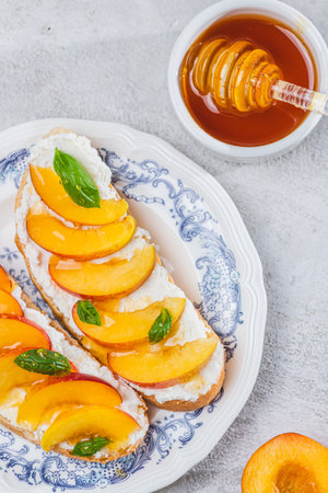 Bruschetta with ricotta cheese, sliced nectarines, basil and honey on a plateの写真素材
