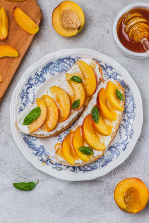 Bruschetta with ricotta cheese, sliced nectarines, basil and honey on a plateの写真素材