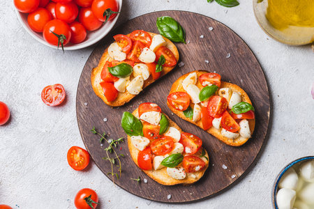 Bruschetta caprese with cherry tomatoes and mozzarella garnished with basilの写真素材