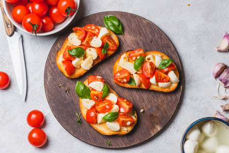 Bruschetta caprese with cherry tomatoes and mozzarella garnished with basilの写真素材