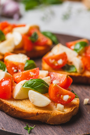 Bruschetta caprese with cherry tomatoes and mozzarella garnished with basilの写真素材