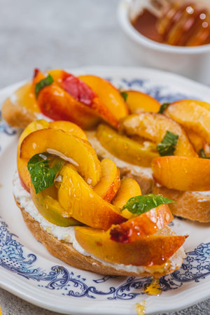 Bruschetta with ricotta cheese, sliced nectarines, basil and honey on a plateの写真素材