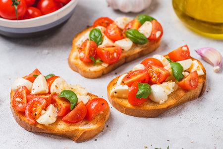 Bruschetta caprese with cherry tomatoes and mozzarella garnished with basilの写真素材
