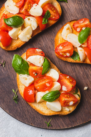 Bruschetta caprese with cherry tomatoes and mozzarella garnished with basilの写真素材