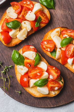 Bruschetta caprese with cherry tomatoes and mozzarella garnished with basilの写真素材