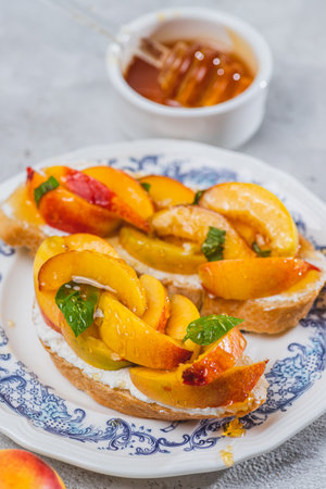 Bruschetta with ricotta cheese, sliced nectarines, basil and honey on a plateの写真素材
