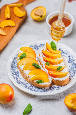 Bruschetta with ricotta cheese, sliced nectarines, basil and honey on a plateの写真素材