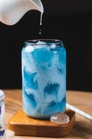 Milk is added to a glass of blue teaの写真素材