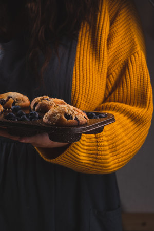 A stack of blueberry muffins in the hands of a womanの写真素材