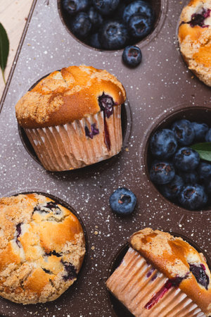 Blueberry muffins on a rustic table in a moldの写真素材