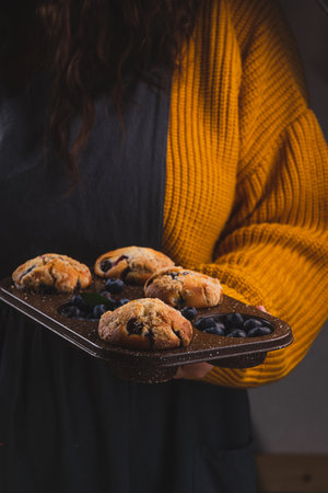 A stack of blueberry muffins in the hands of a womanの写真素材
