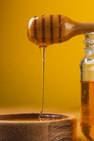 A jar of honey and a spoon, honey is pouringの写真素材