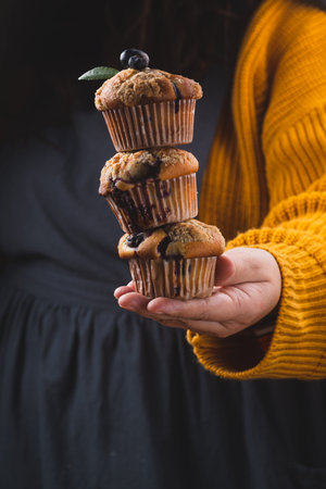 A stack of blueberry muffins in the hands of a womanの写真素材