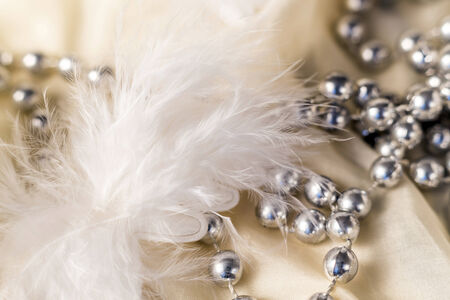 Christmas decorations with feather and necklace on satin backgroundの写真素材