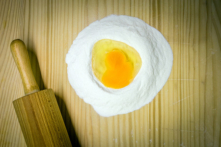 flour and eggs on a wooden board, production of pastaの写真素材