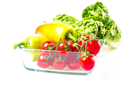 Bunch of vegetables in the glass jar. Red tomato, yellow pepper and green salad on white background.の写真素材