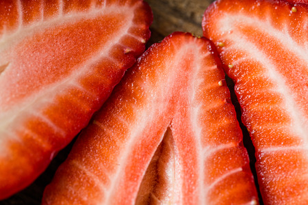 fresh strawberries cut in half on a wooden tableの写真素材