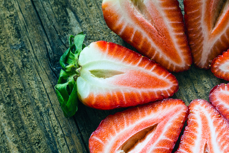 fresh strawberries cut in half on a wooden tableの写真素材