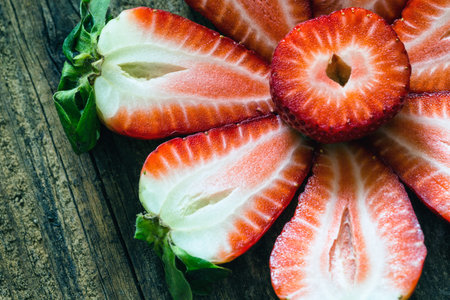 fresh strawberries cut in half on a wooden tableの写真素材