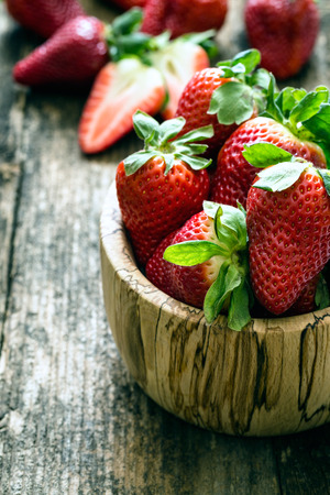 wooden bowl of fresh strawberries on old wooden tableの写真素材