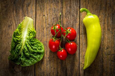 Bunch of vegetables, red tomato, pepper and green salad on a wood table.の写真素材