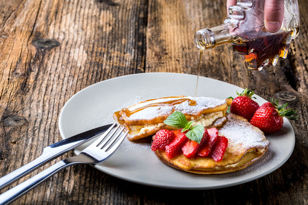 filled with homemade pancakes with strawberries and maple syrupの写真素材