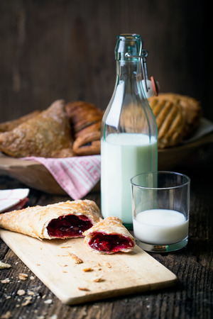 assorted breakfast pastries with jam and milk on old wooden tableの写真素材